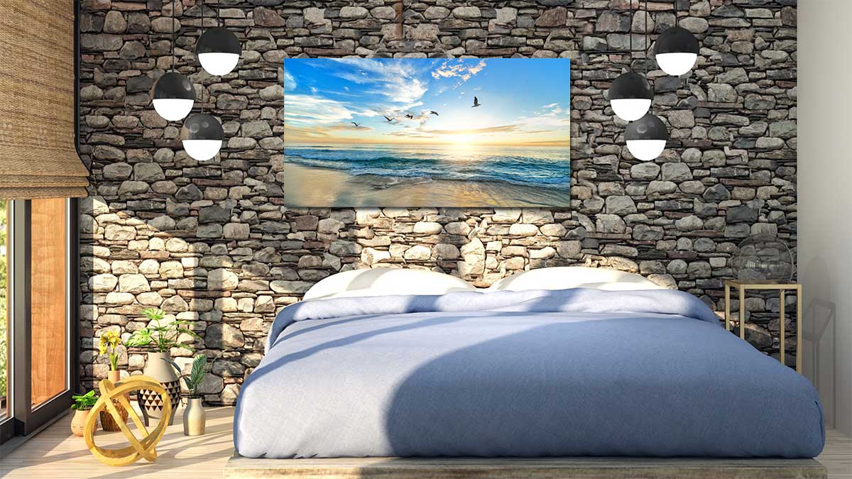 Picture of birds in flight over the sea, printed into a large panoramic poster hanging on a stone wall in a bedroom
