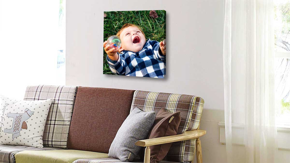 Canvas print showing a capture of a young child laughing whilst rolling on the grass