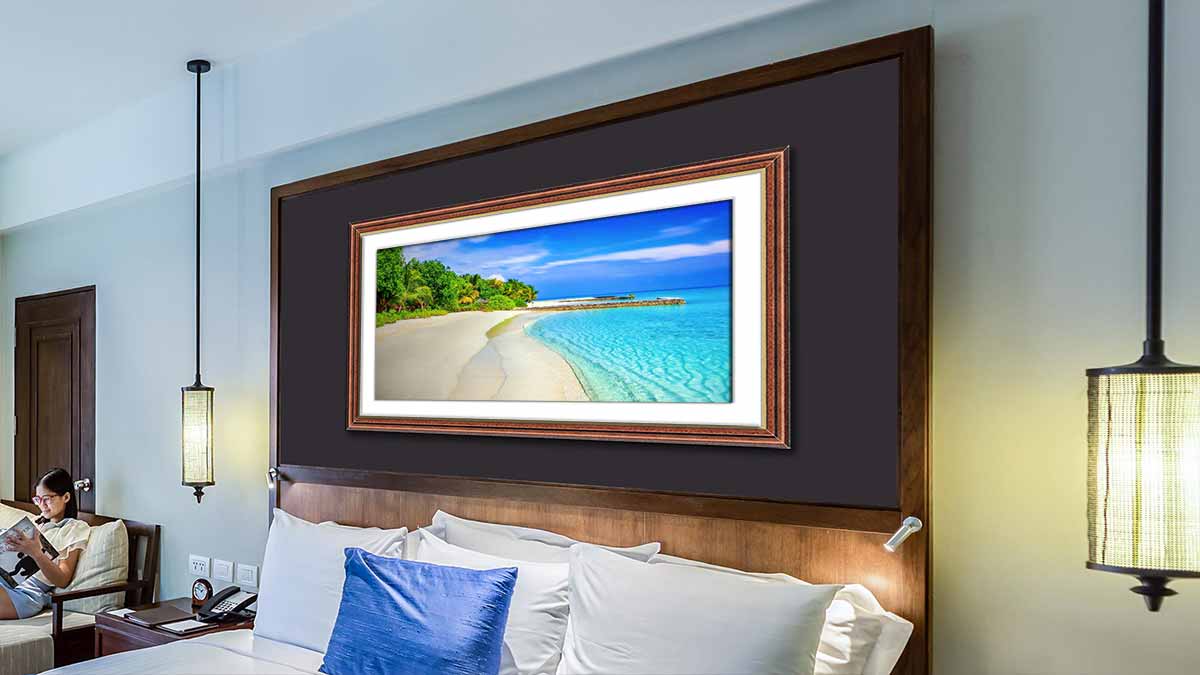 Tropical beach landscape framed in a stained wooden frame with a gold sight edge and hung over a bed.