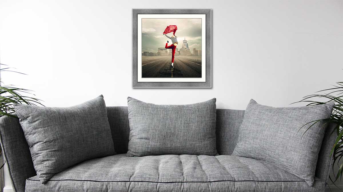 Beautiful capture of a dancer with a red scarf in a grey wood frame hung over a comfy grey sofa