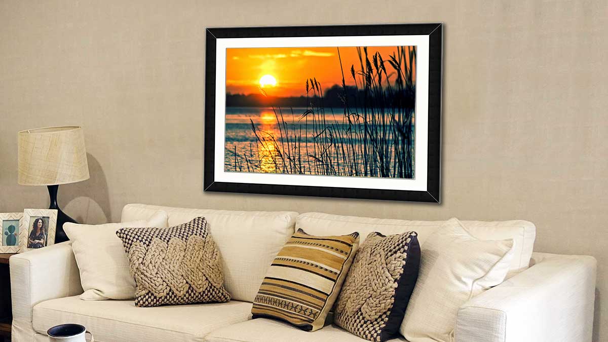 Sunset over a lake taken with a mobile phone, printed and framed and hung above a cream coloured sofa
