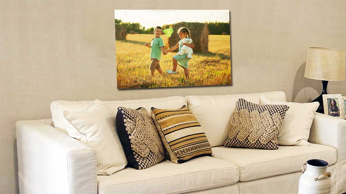 Picture of two children playing in a hay field taken with a digital slr and printed on a classic size poster, hanging above a comfy settee.