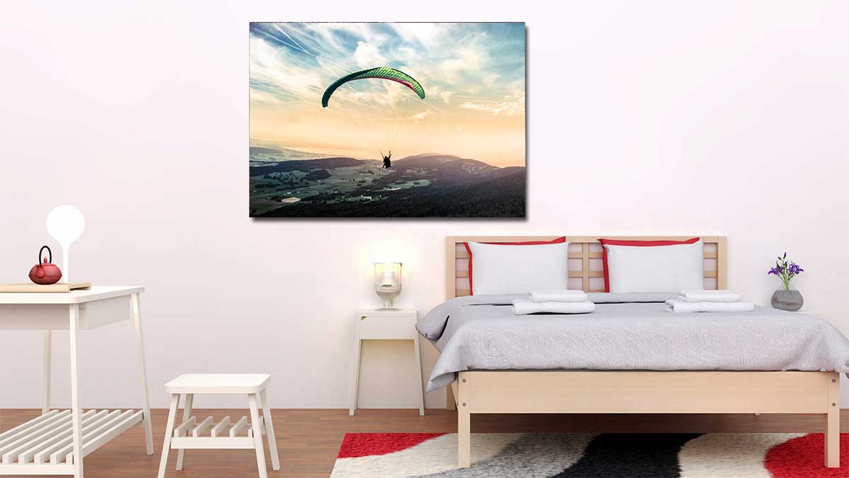 Image of a hang glider over a breathtaking sunrise landscape, printed on a standard style poster and hung in a bedroom