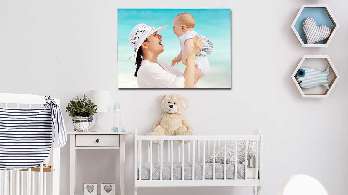 Picture of a baby being held by its mum, printed on a standard poster and hung above a crib in a nursery