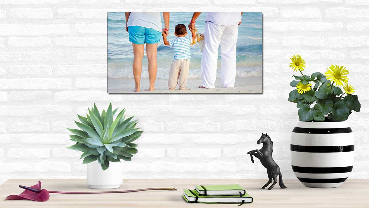 Photo of a family by the seaside on a poster hanging on a white brick wall