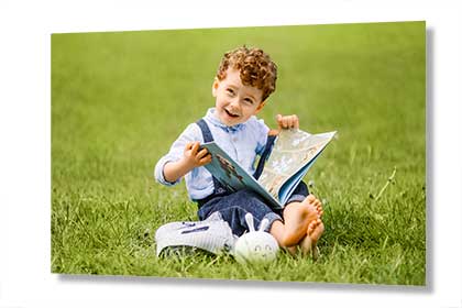 Poster print of a young boy sitting on the grass reading a book