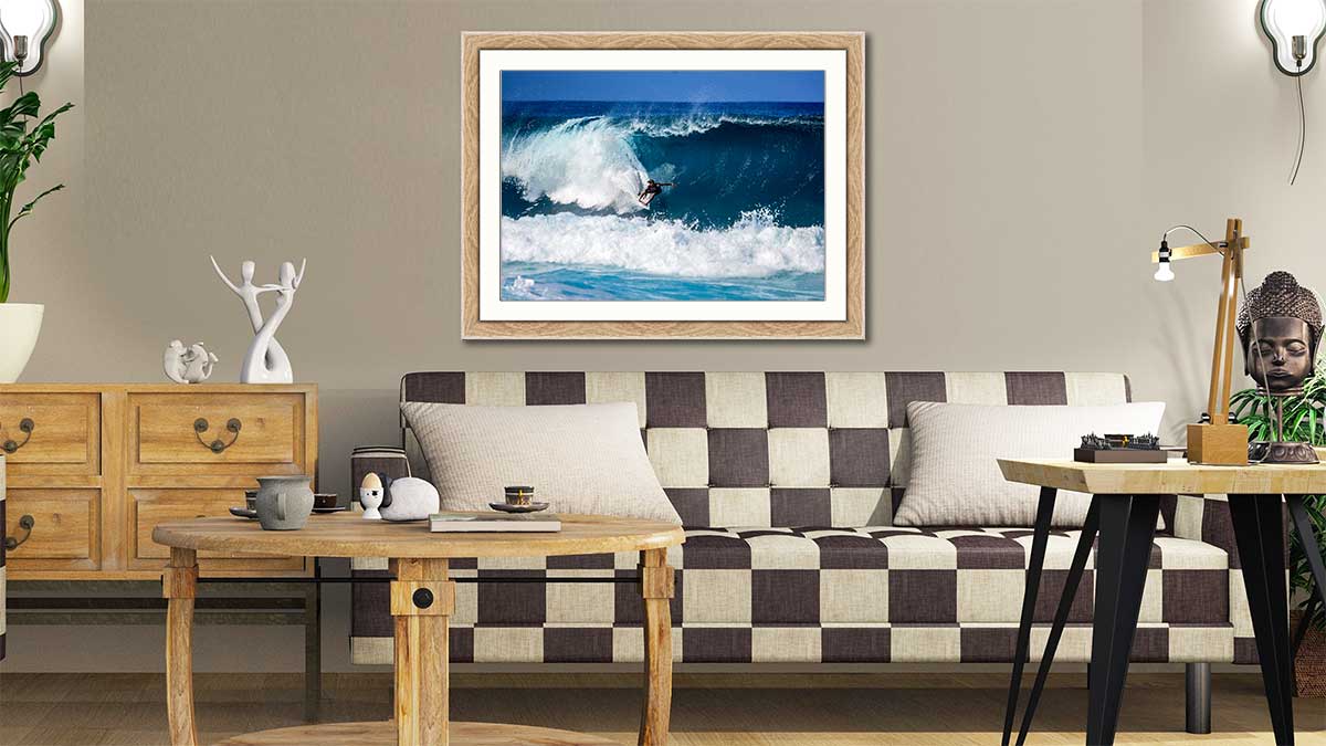 Picture of a surfer riding a wave in a natural wood frame hung in a neutrally decorated sitting room