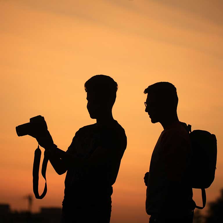 Photo of two men taking a photo of a sunset