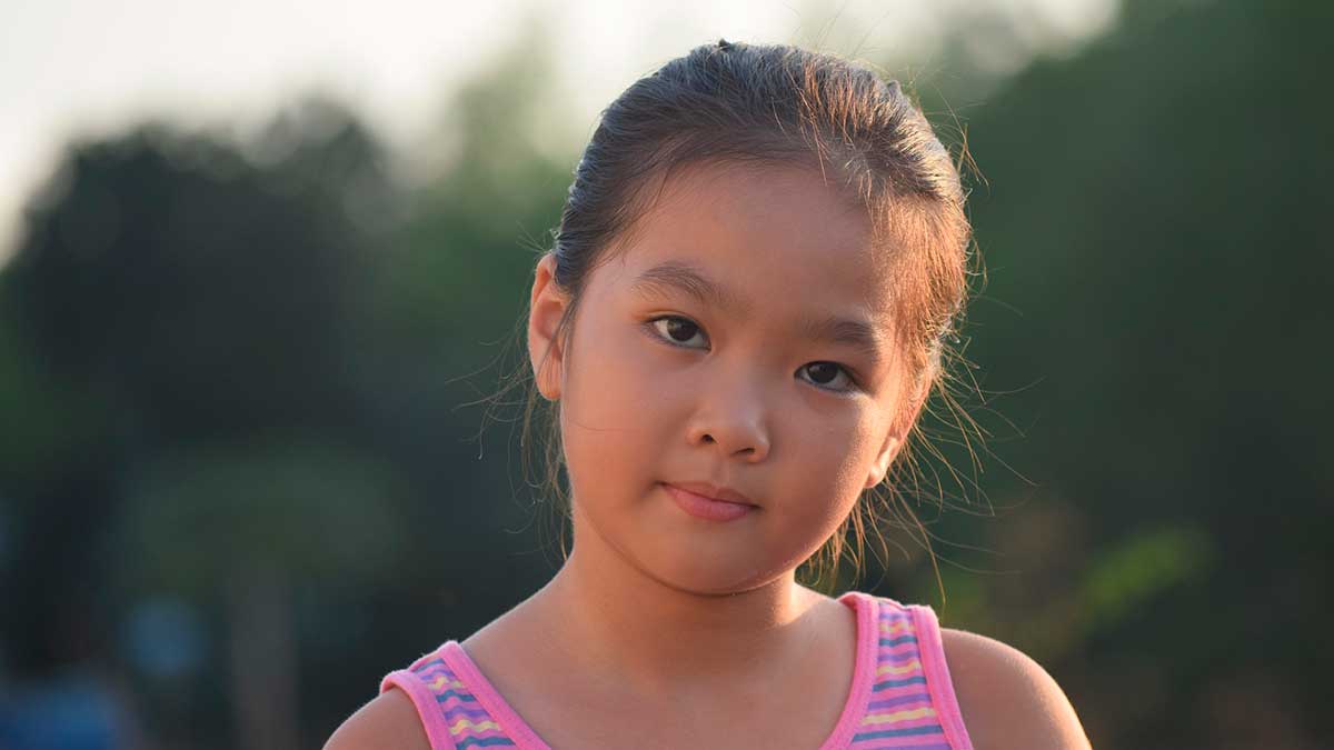 Portrait of a young girl standing in the twilight with the setting sun shinning on the side of her face