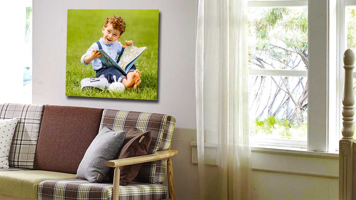 Square poster of a child reading a book sitting on the grass on the wall in a family home