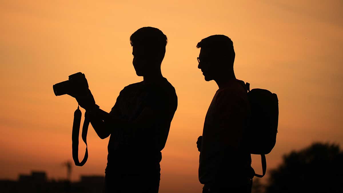 Two men taking photos in the sunset